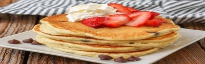 Stack of fluffy pancakes with syrup and berries